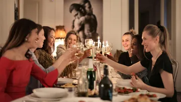 Sieben Frauen stoßen an Gläsern während eines Abendessens.